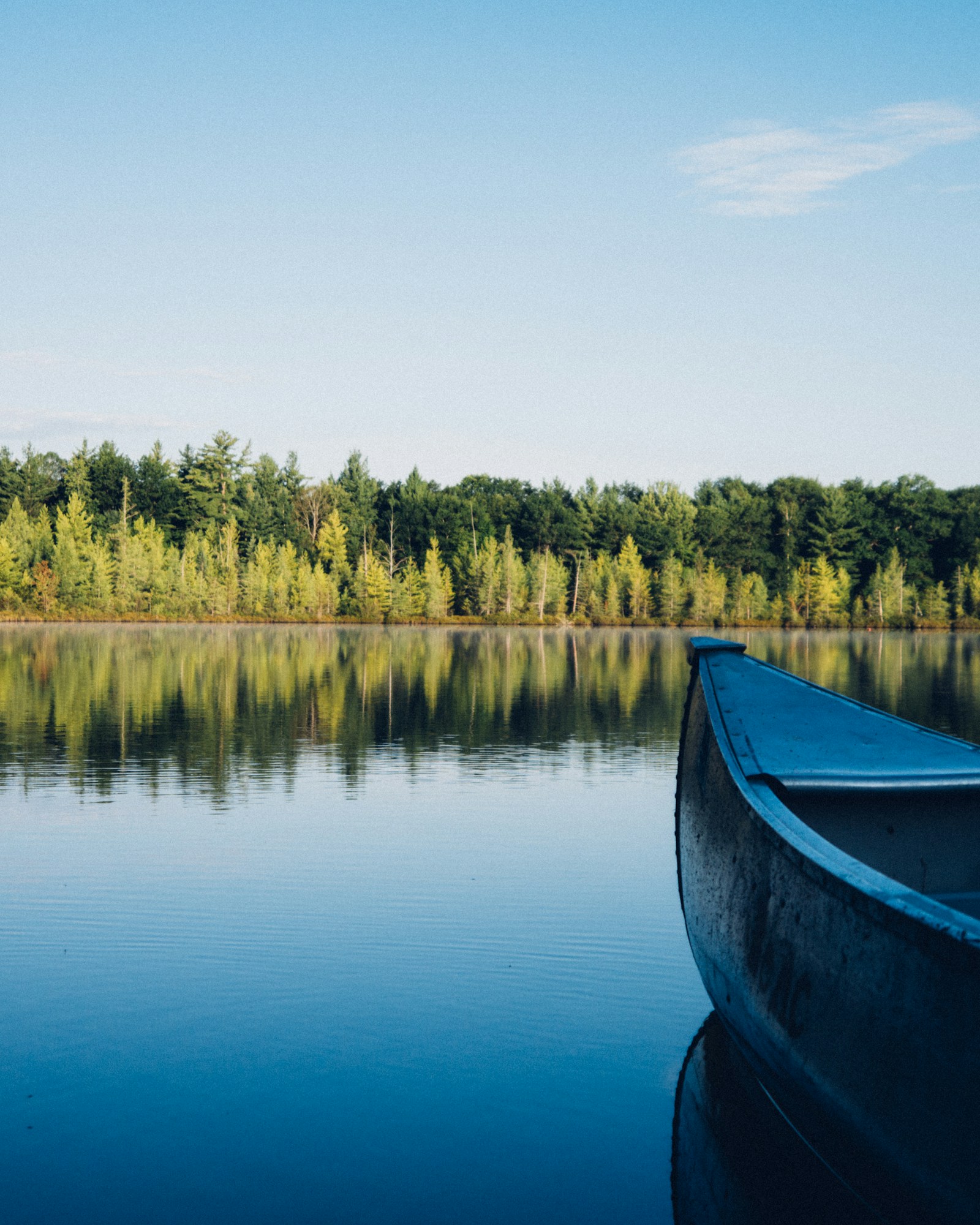 Canoa azul parada junto à margem em dia calmo e claro, condições seguras para remar