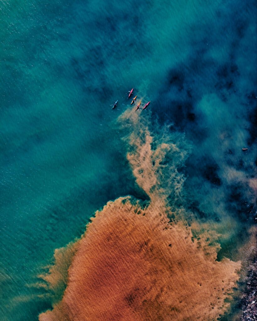 Caiaques coloridos vistos de cima alinhados em água turquesa, comparação de modalidades