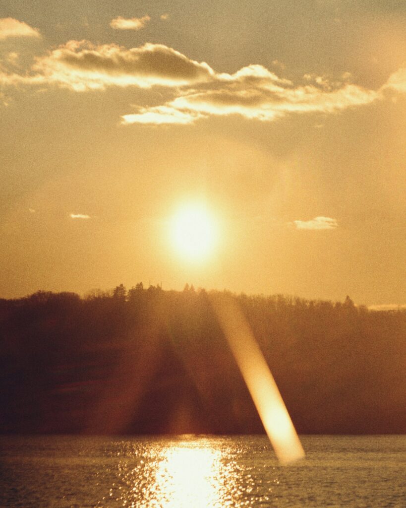 Céu suave de amanhecer com nuvens refletidas na água parada do Lago Paranoá