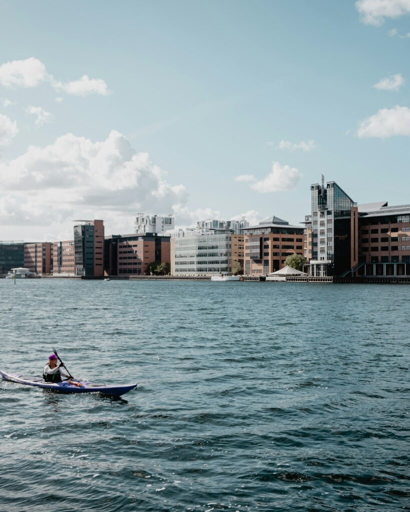 Grupo pequeno em contraluz na margem aprendendo a remar em manhã clara — turma Capital do Remo